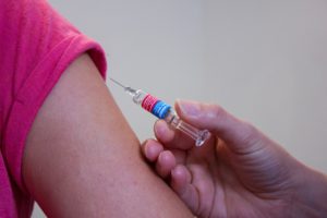 vaccination needle next to an adult's arm